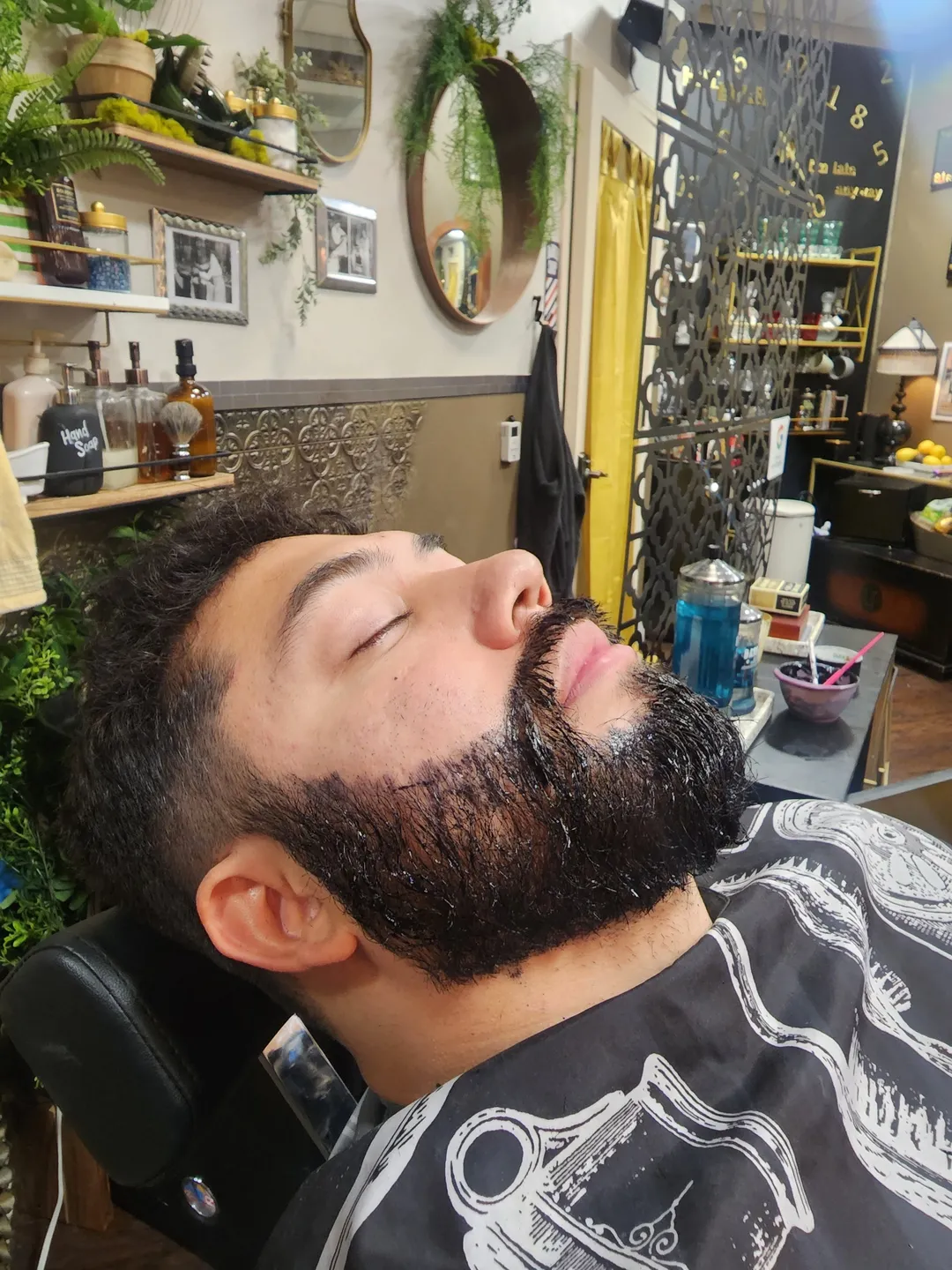 A client reclined in the barber chair mid beard trim at The Gentle Jerks Barber Club