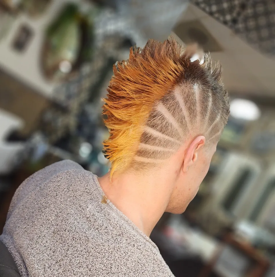 A client with a bright copper mohawk and a shaved line design